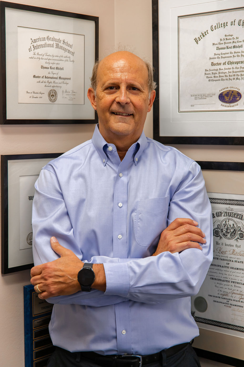 Dr. Thomas Mitchell, DC, in his Raleigh practice, framed diplomas behind him